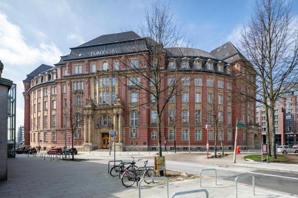 汉堡Fraser Suites Hamburg的一座大型砖砌建筑,前面停放着自行车