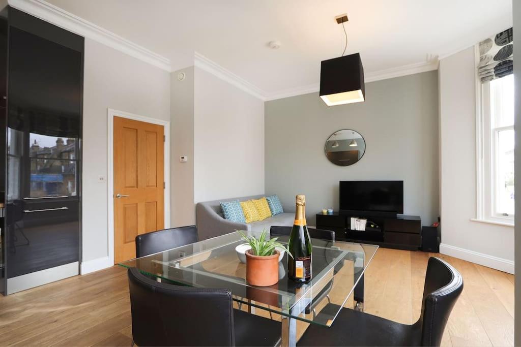 伦敦Comfy 1 bed flat in Tufnell Park的客厅配有玻璃桌和一瓶葡萄酒