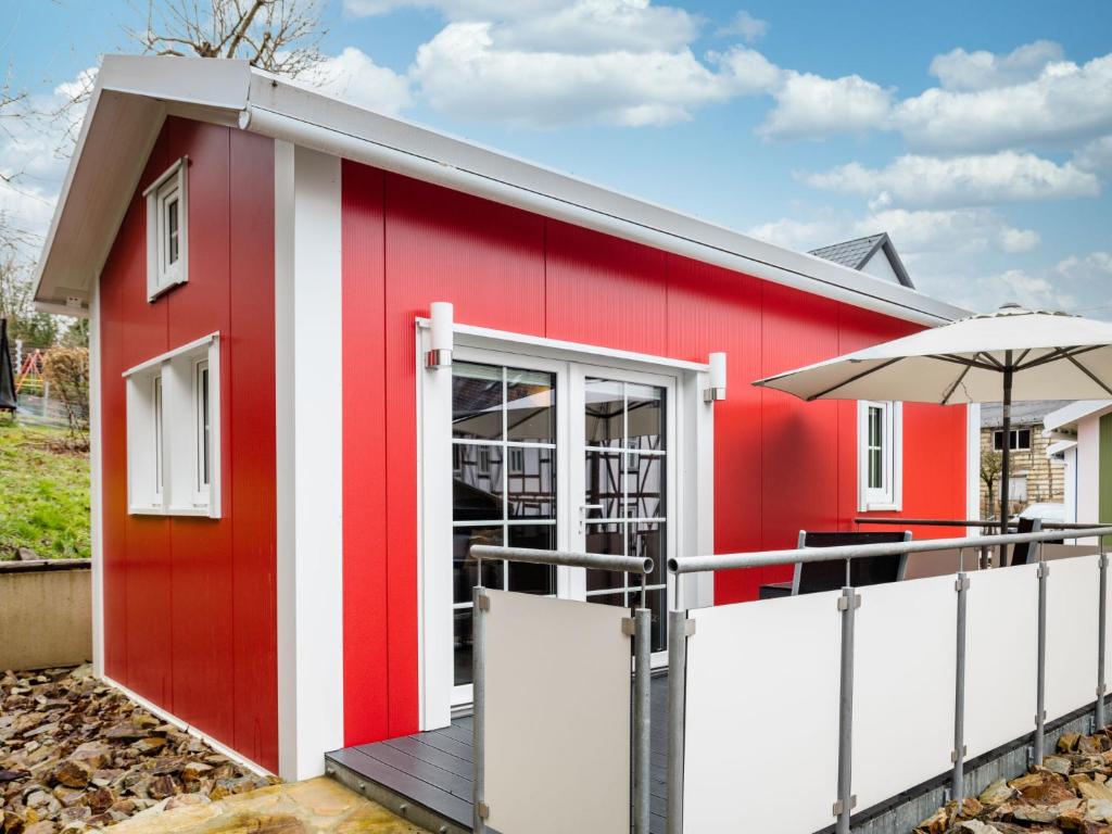 巴特马林贝格Holiday Home Tiny Haus Westerwald 16 Red by Interhome的一座红色和白色的建筑,配有雨伞