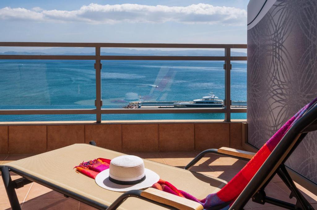 圣加利尼Minos Boutique Hotel的坐在带游轮的阳台椅子上的帽子