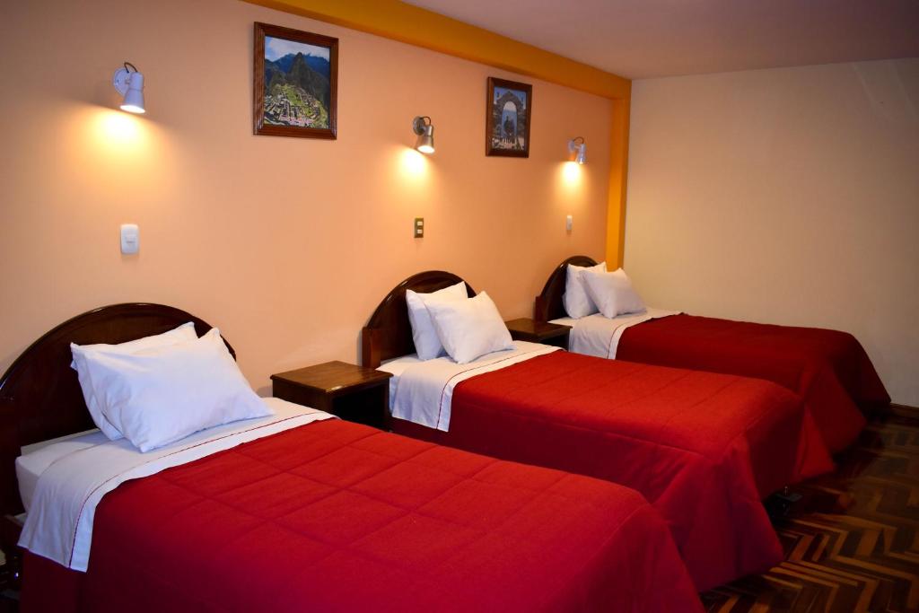 普诺Hostel Sol Andina Inn的酒店客房,配有两张带红色床单的床