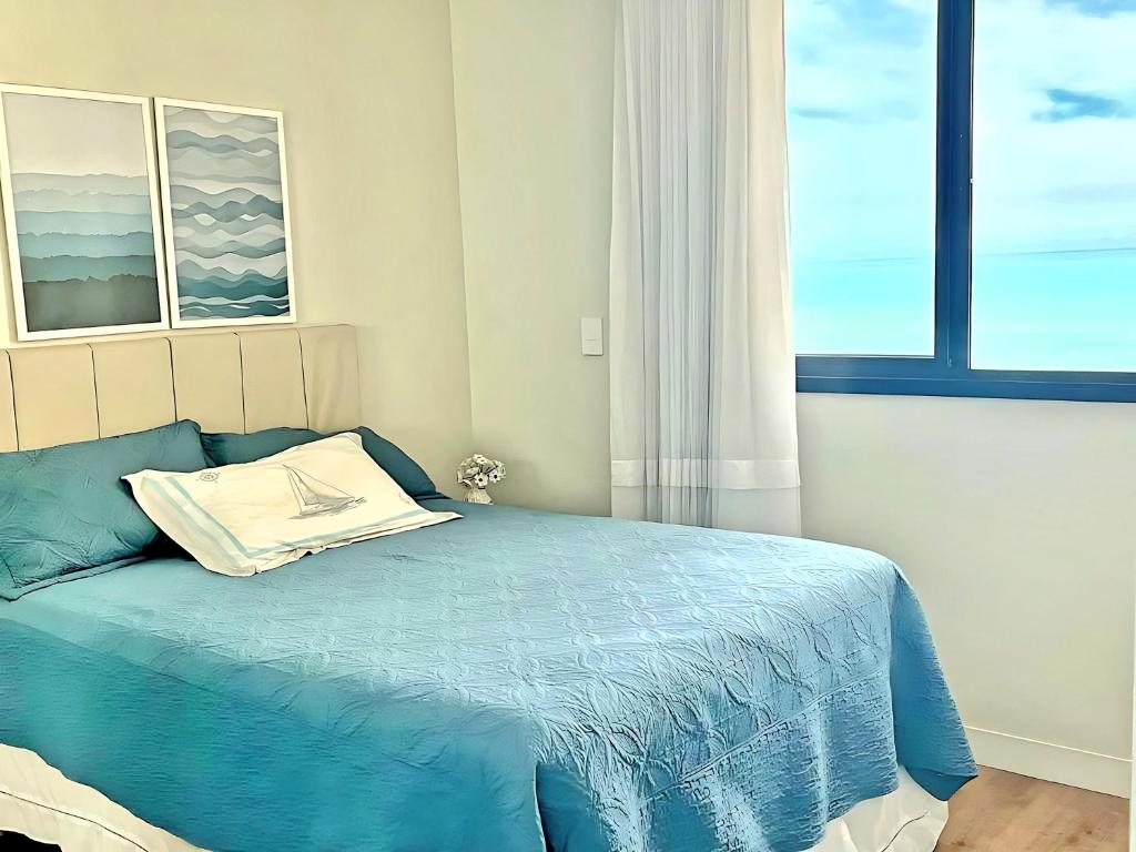 瓜拉派瑞Apartamento Quartos Vista Praia do Morro Casais Melhor Localização, Super Completo 4 TVs Led, Camas-box Novas, 2 Quartos Suíte, Garagem, 2 Ar Condicionados, Wifi 300mb, Varanda Gourmet, Cervejeira, Novo para Famílias的一间卧室设有蓝色的床和窗户。