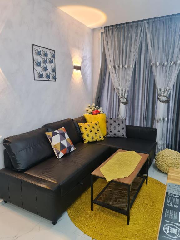 纳哈里亚Reem Suite的客厅配有黑色真皮沙发和黄色枕头。