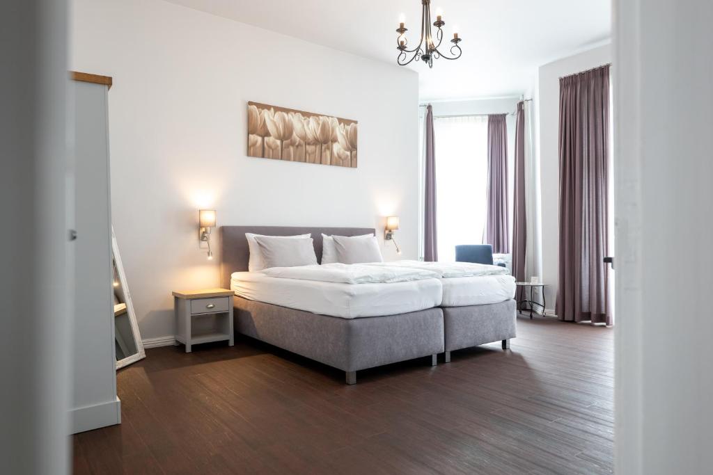 韦斯特兰Maritas Logierhaus (Haus Braunschweig)的白色卧室配有一张床和一个吊灯