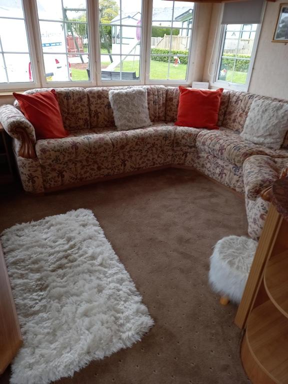 沃金顿Adorable Caravan in Western Lakes的客厅的沙发,配有红色和白色枕头