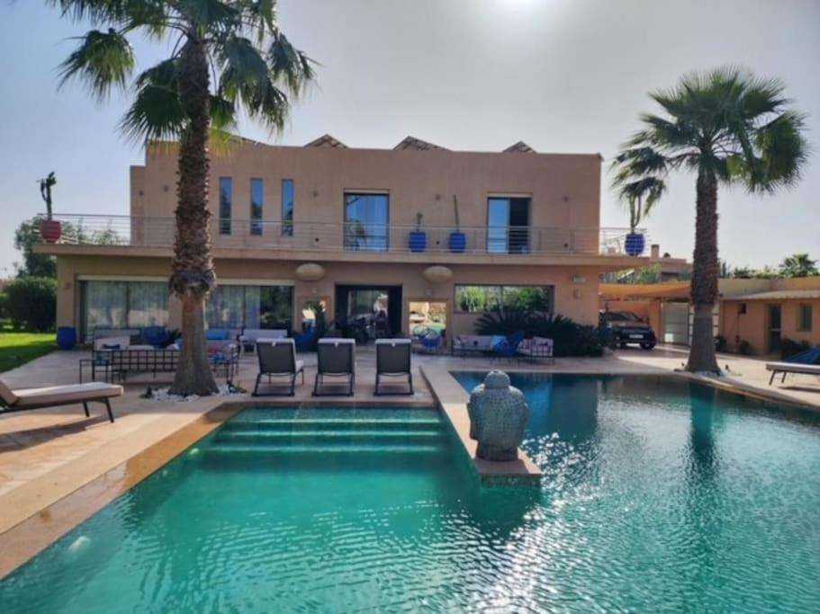 马拉喀什Villa de rêve à Marrakech的一座带游泳池和棕榈树的房子