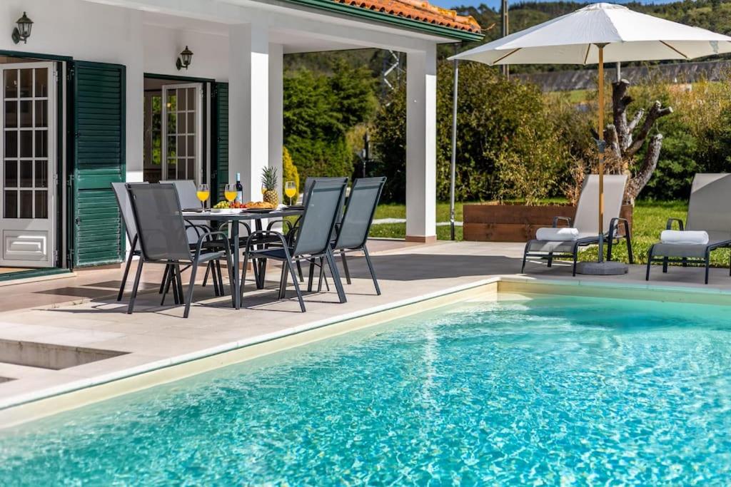 FamalicãoVilla Coral - Private Heated Pool & Hot tub的游泳池旁带桌椅的天井