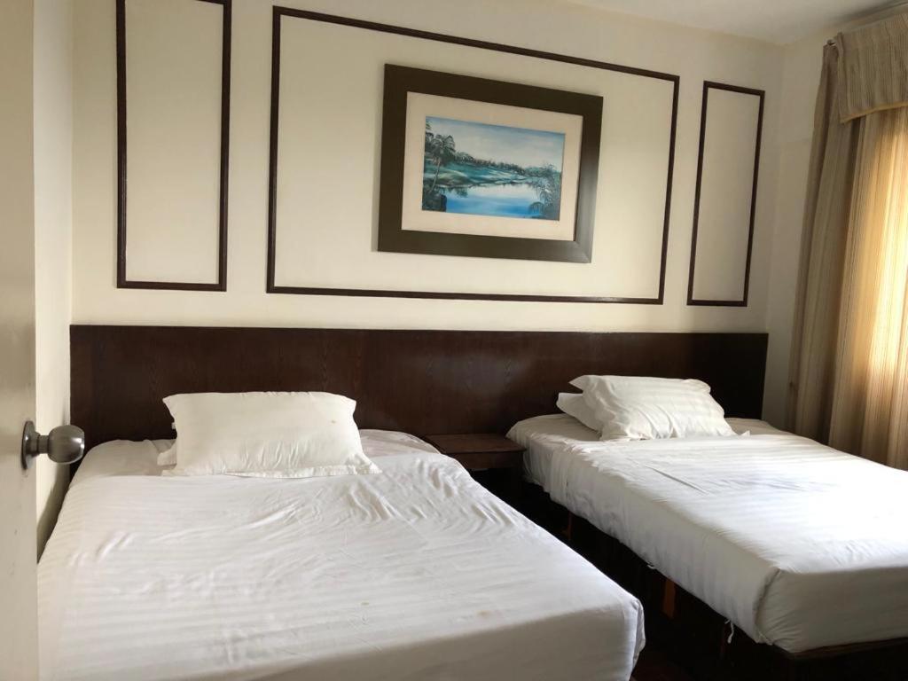 Kampong Alor GajahAisis Home at Afamosa的配有白色床单的酒店客房内的两张床