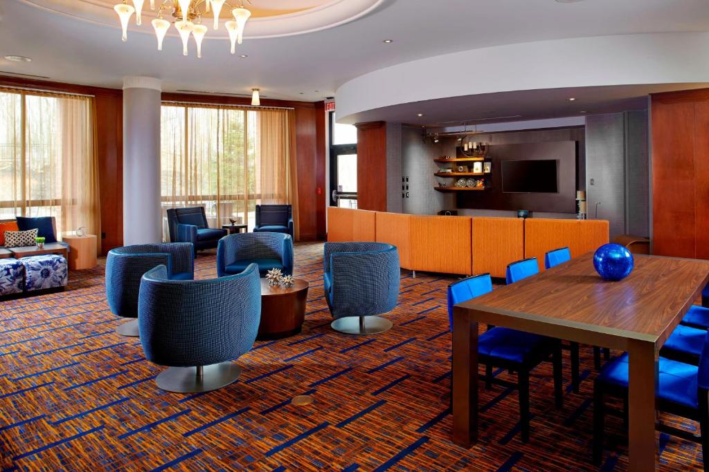 格林斯堡匹兹堡格林万怡酒店的酒店大堂设有桌椅和沙发。
