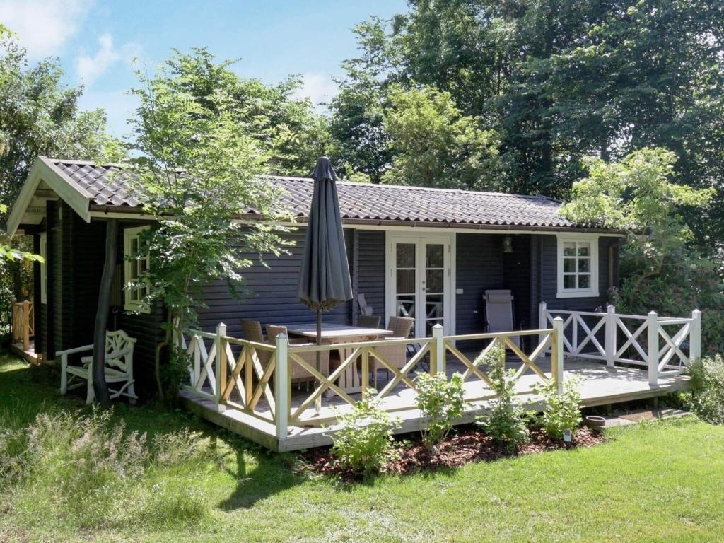 瓦伊比Holiday Home Lindehøjen的庭院里带雨伞的蓝色小屋