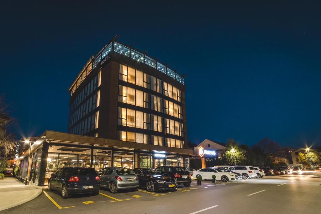 波德戈里察Bristol Hotel Podgorica的停车场内有车辆停放的高楼