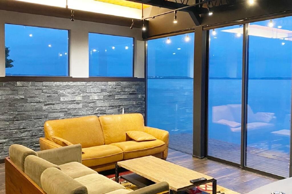 三沢市Tiny resort misawa的客厅设有黄色的沙发和窗户。