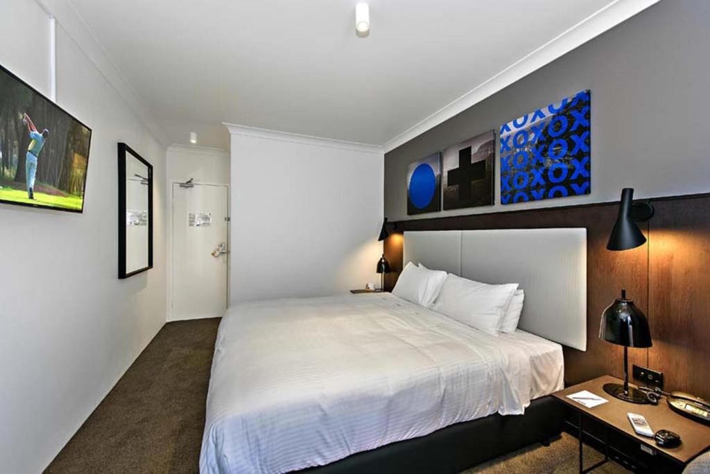 悉尼CKS Sydney Airport Hotel的卧室配有一张白色大床和一张书桌