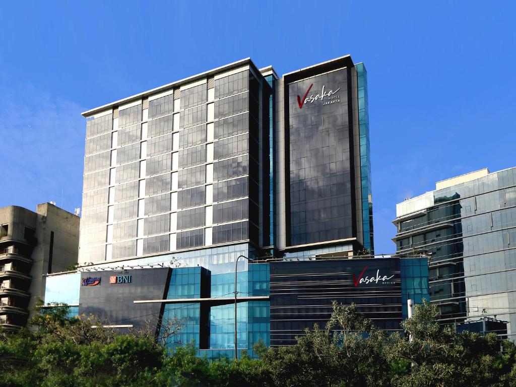 雅加达Vasaka Hotel Jakarta Managed by Dafam的一座高大的建筑,旁边有一个标志