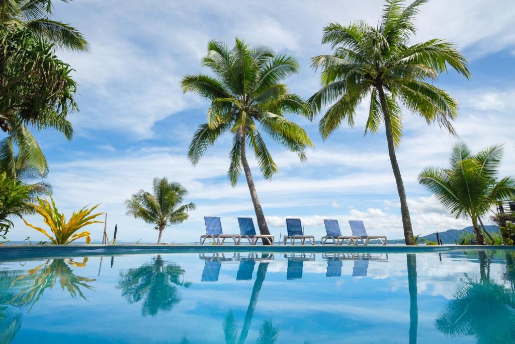 南迪斐济俱乐部度假酒店的一个带棕榈树和躺椅的游泳池
