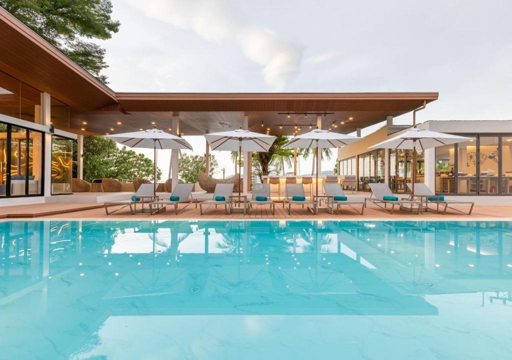 芭东海滩LIV Hotel Phuket Patong Beachfront的一个带椅子和遮阳伞的游泳池