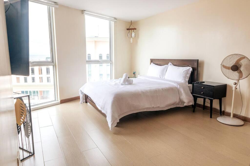马尼拉Cozy 2-bedroom in The Venice Luxury Residences的卧室配有一张白色大床和风扇