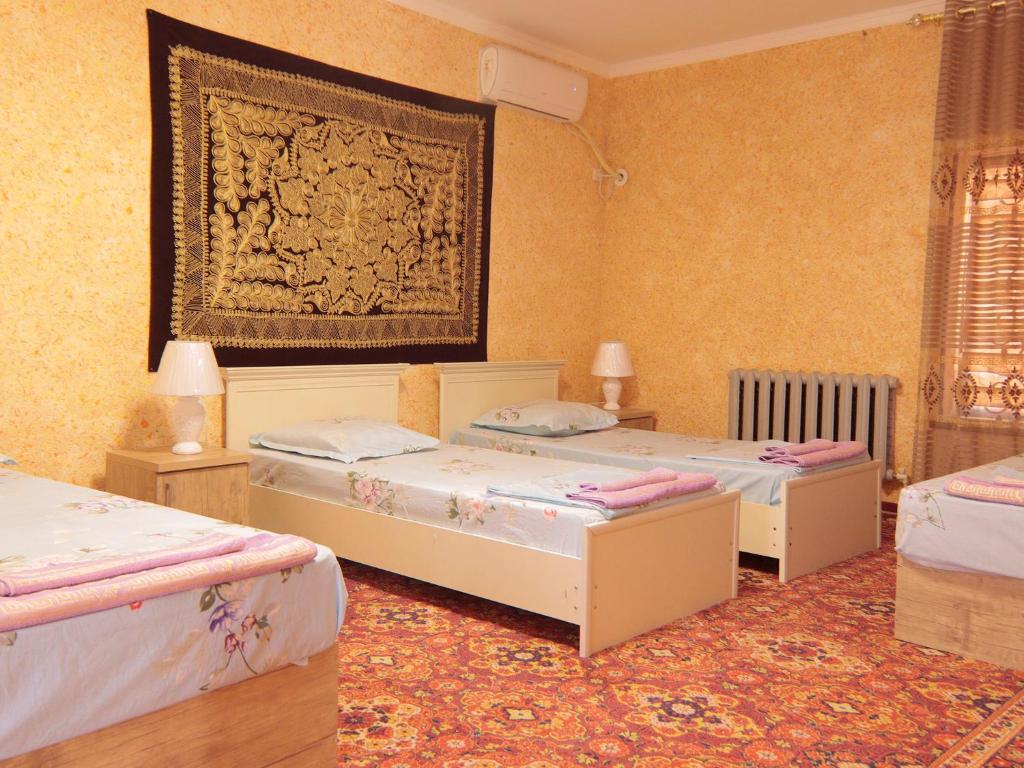 布哈拉LION Guest House的一间卧室设有三张床,墙上挂着一幅画