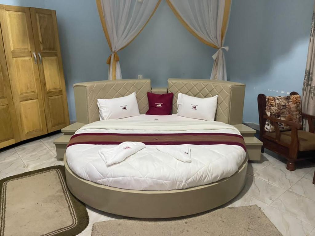 姆巴拉拉Dreamwood suites Mbarara的一间卧室配有一张大床,配有白色床单和红色枕头