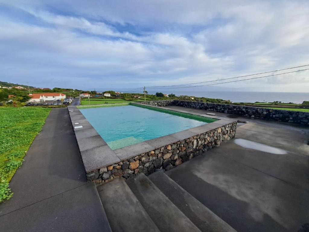 Companhia de BaixoCasas da Prainha C的一座游泳池,周围环绕岩石,毗邻大海