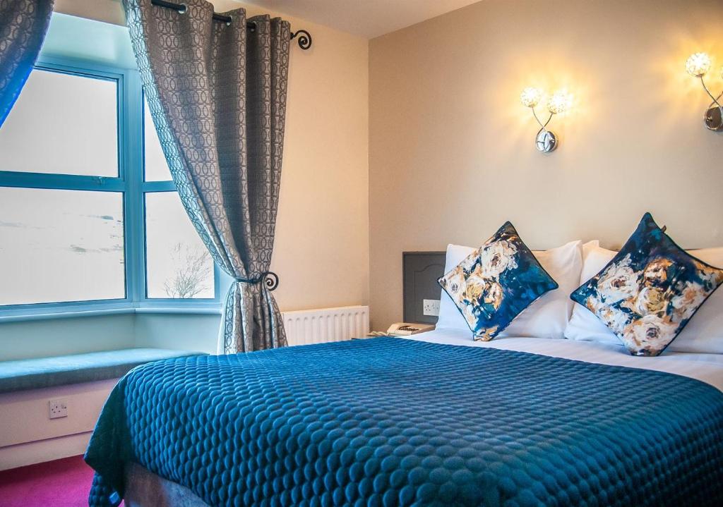邓法纳希Arnolds Hotel的一间卧室配有一张带蓝色毯子的床和窗户。