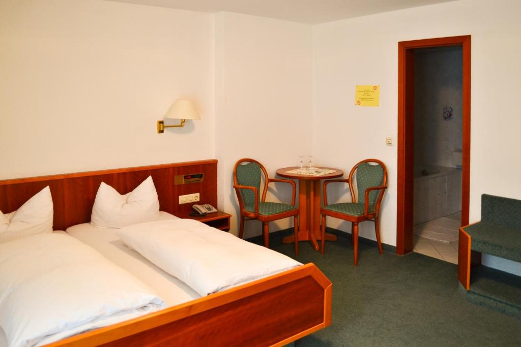 弗莱堡欢乐乡村酒店的卧室配有一张床和一张桌子及椅子