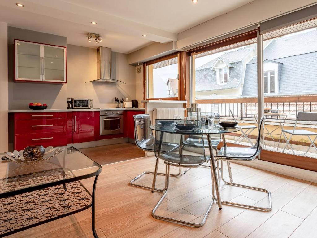 多维尔Apartment Les Cigognes by Interhome的一间厨房,配有红色橱柜和玻璃桌
