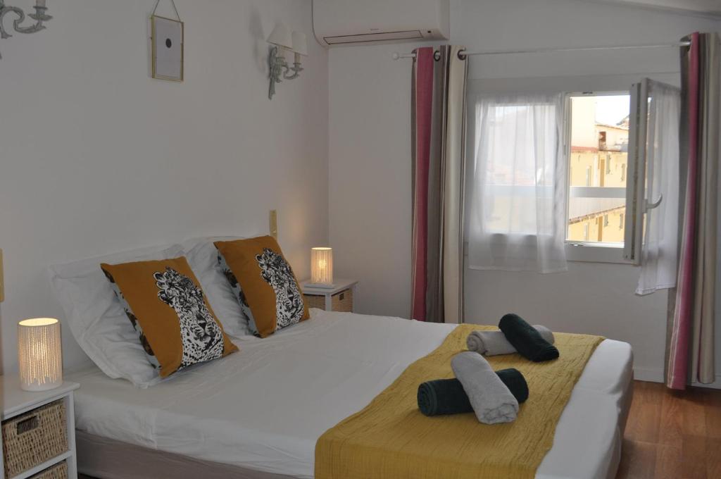 博尼法乔Appartement duplex plein sud sur le port de Bonifacio的卧室配有带枕头的白色床和窗户。
