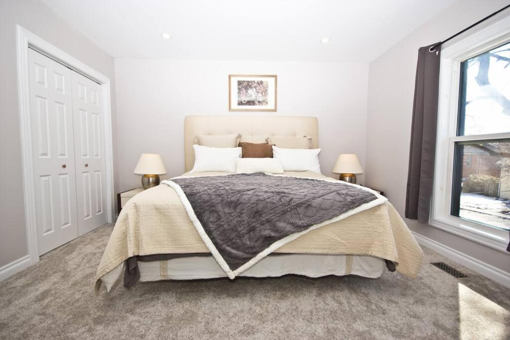 彼得伯勒Stylish Home For A Perfect Stay for 4!的一间卧室配有一张床、两盏灯和一个窗户。