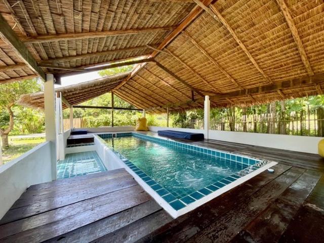 湄登La Maison - Chiangmai的一座铺有木地板并设有屋顶的室内游泳池