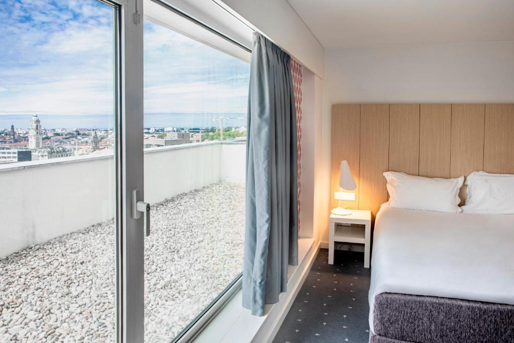 波尔图普瑞图森特瑞达酒店的一间卧室设有一张床和一个美景阳台