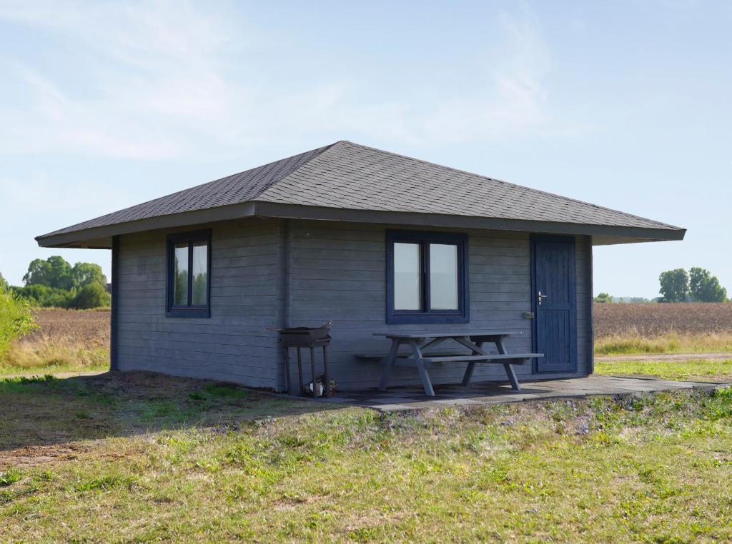 DurbeVītolu dīķi - atpūtas mājiņas ar makšķerēšanu的小屋前面设有野餐桌