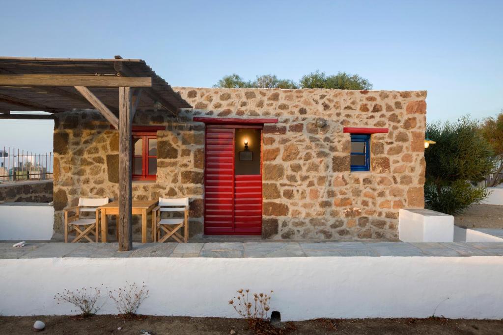 特里皮蒂Marketos Windmill and Houses的石头房子,设有红色的门和桌椅