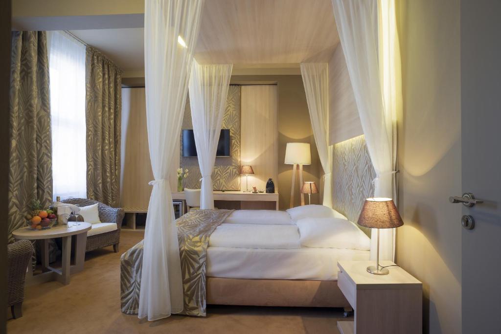 布拉格Pytloun Kampa Garden Hotel Prague的一间带天蓬床的卧室和一间客厅