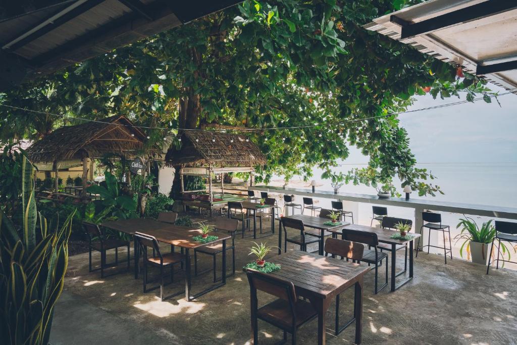 苏梅岛Chill Inn Lamai Hostel & Beach Cafe的树下设有桌椅的餐厅