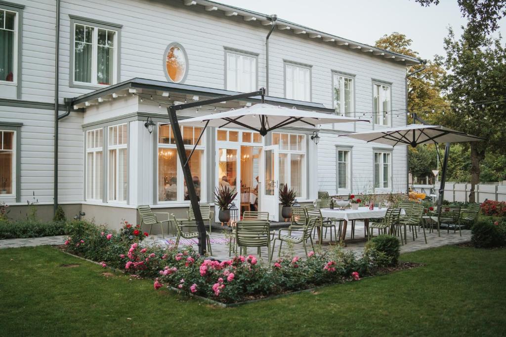 哈普萨卢Old Hapsal Hotel的房屋设有带桌子和遮阳伞的庭院