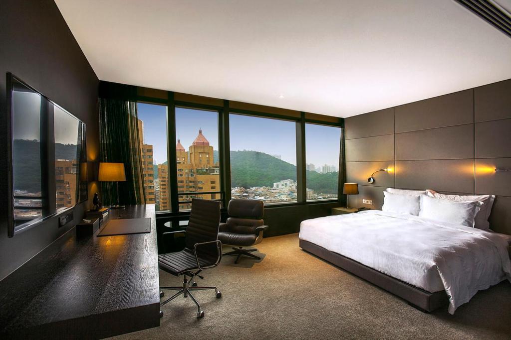 深圳深圳乐酒店的一间卧室配有一张大床和一张桌子及椅子