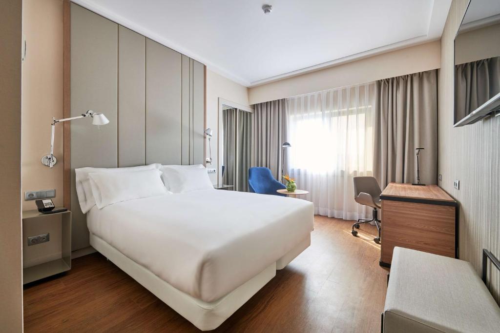里斯本里斯本格兰德营NH酒店的酒店客房设有一张白色大床和一张书桌