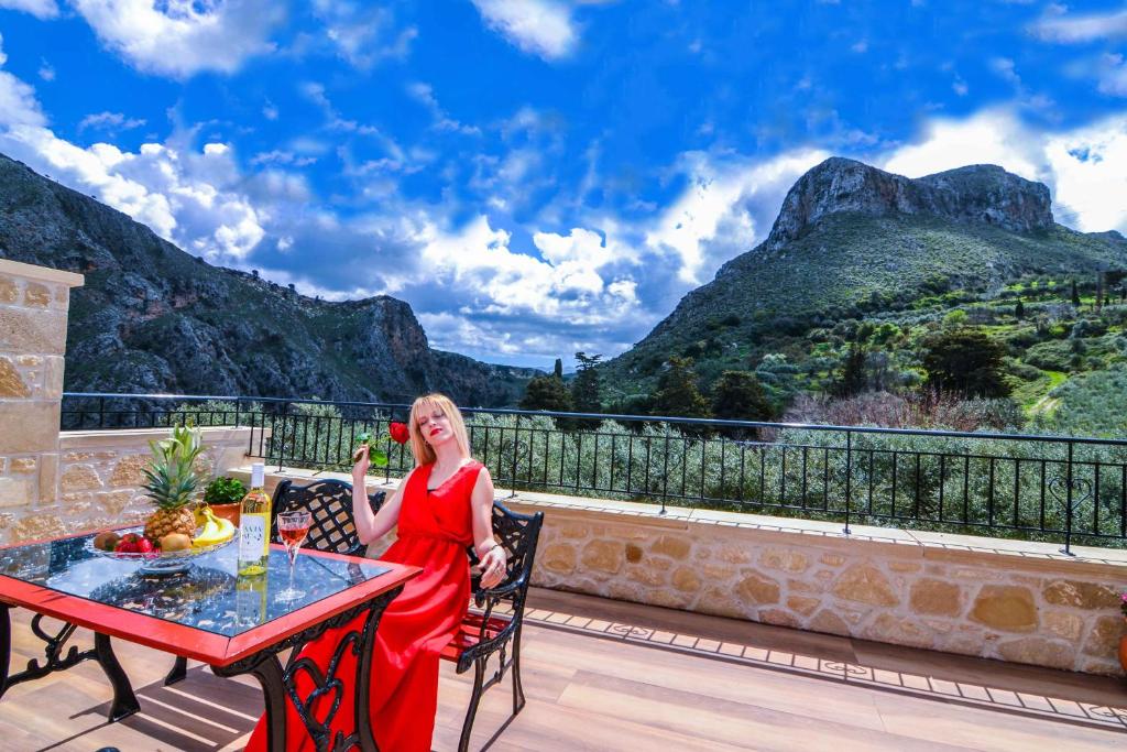 基萨莫斯Villa Anastasia Luxe with Top WiFi, BBQ & Amazing Views的坐在阳台上桌子上的穿着红色衣服的女人
