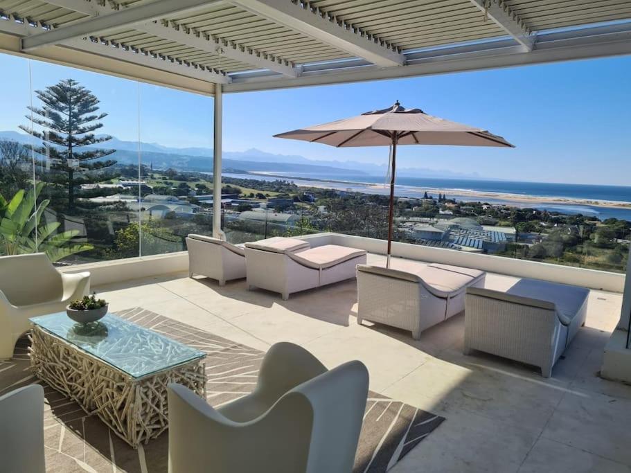 普利登堡湾Contemporary villa with amazing views的庭院配有桌椅和遮阳伞。