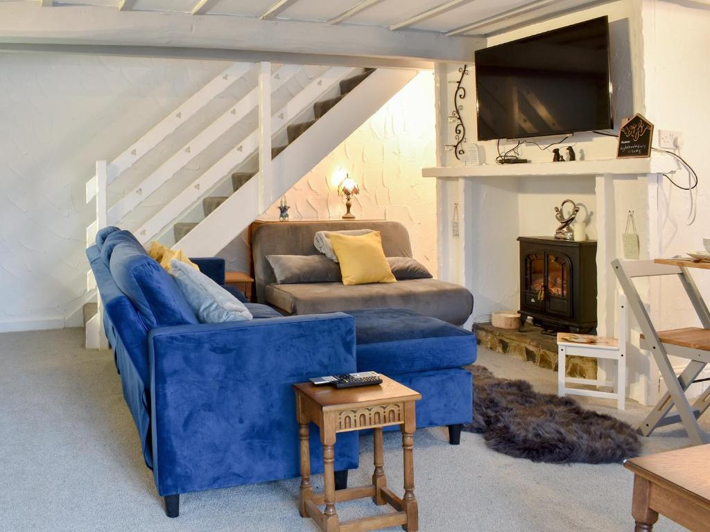 霍姆弗斯Weavers Cottage的客厅配有蓝色的沙发和电视