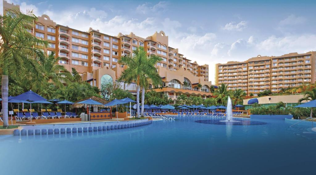 伊斯塔帕阿祖尔伊斯塔帕全包度假酒店的一个带椅子和遮阳伞的大型游泳池的度假酒店