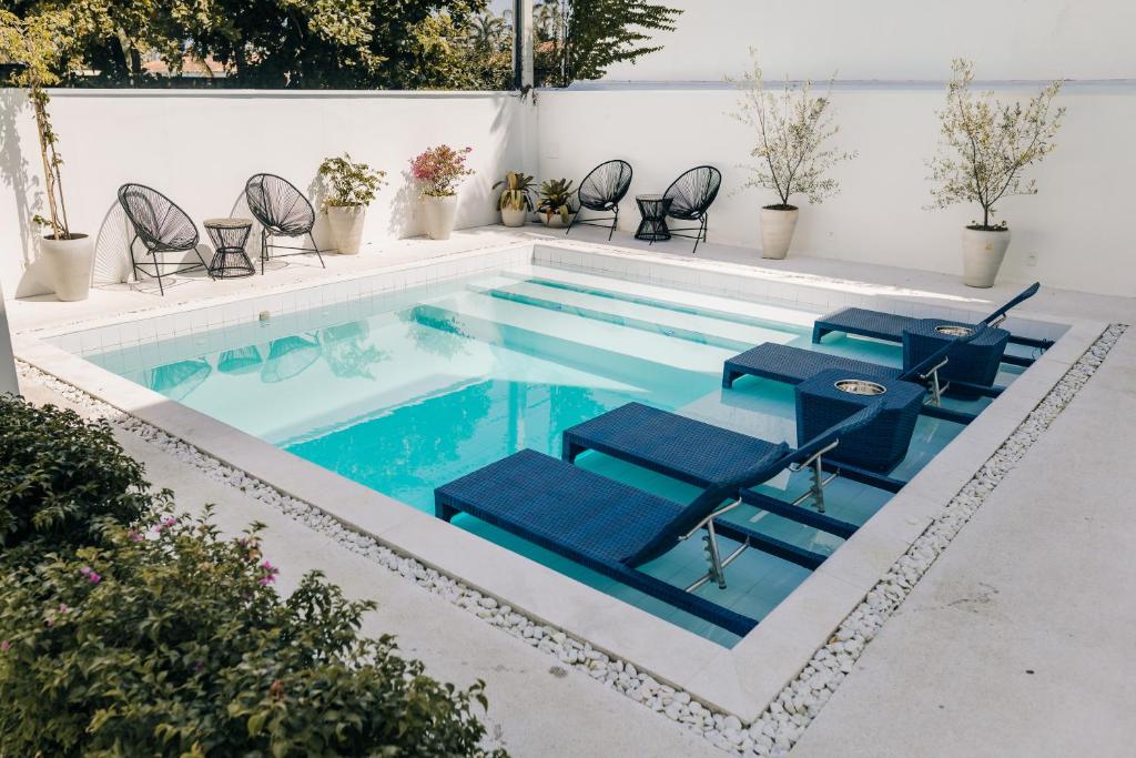 瓜鲁雅Pousada Villa Santô的一个带蓝色椅子的游泳池和一个游泳池
