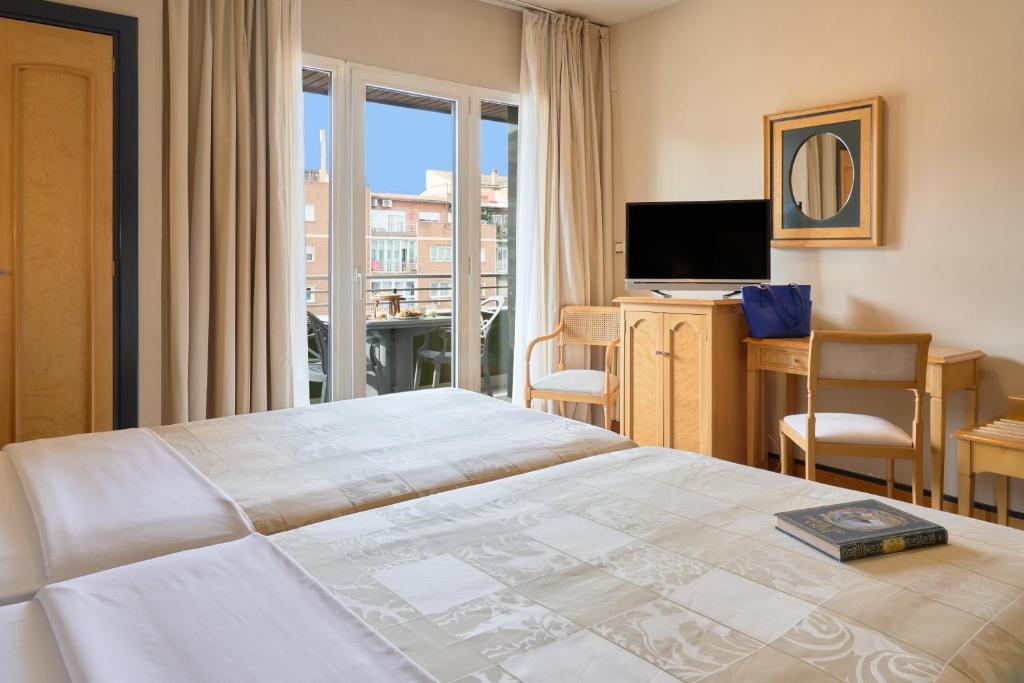 格拉纳达Hotel Macià Cóndor的一间卧室配有一张床、一张书桌和一台电视
