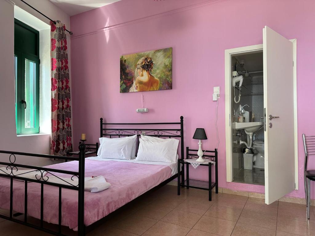 圣加利尼Akteon Rooms的一间卧室配有一张粉红色墙壁的床