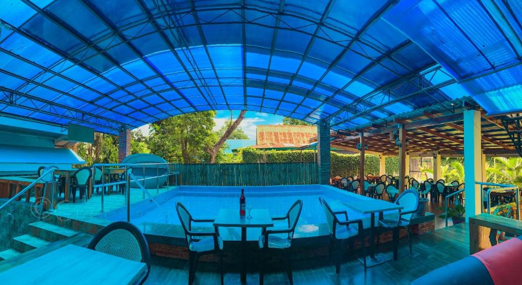 曼巴豪Mabini Hotel的一个带桌椅的游泳池和蓝色的天花板