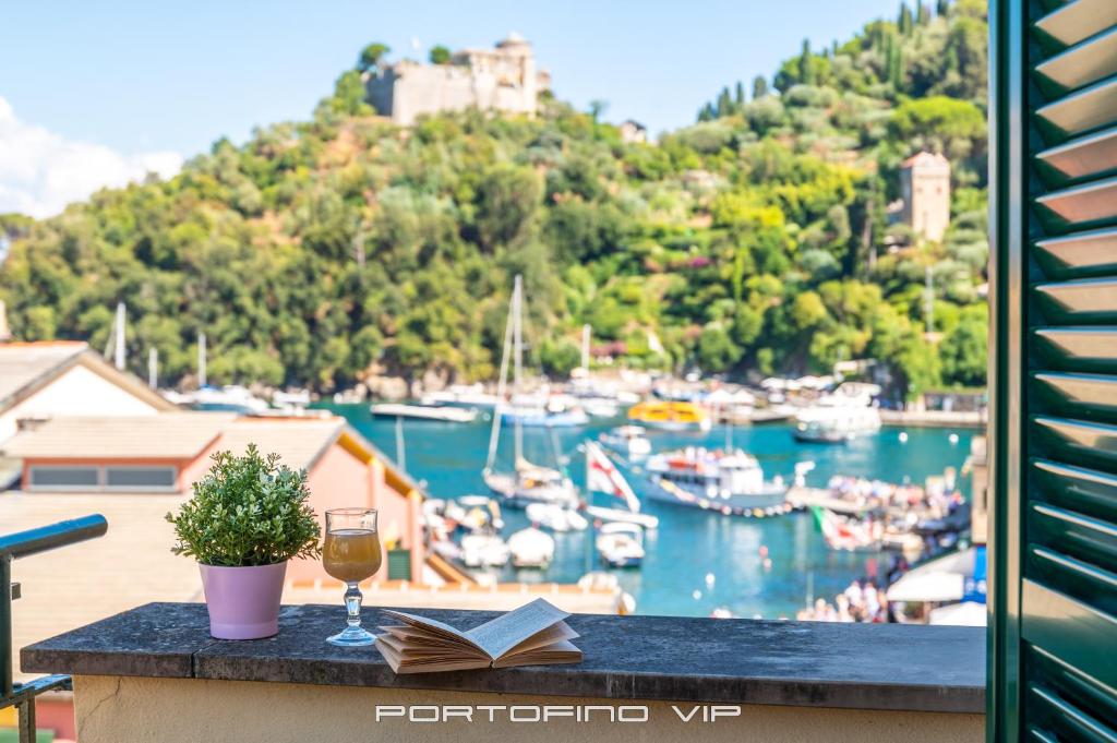 波托菲诺Casa Cristina by PortofinoVip的一杯葡萄酒和一张桌子上的一本书,上面有海港