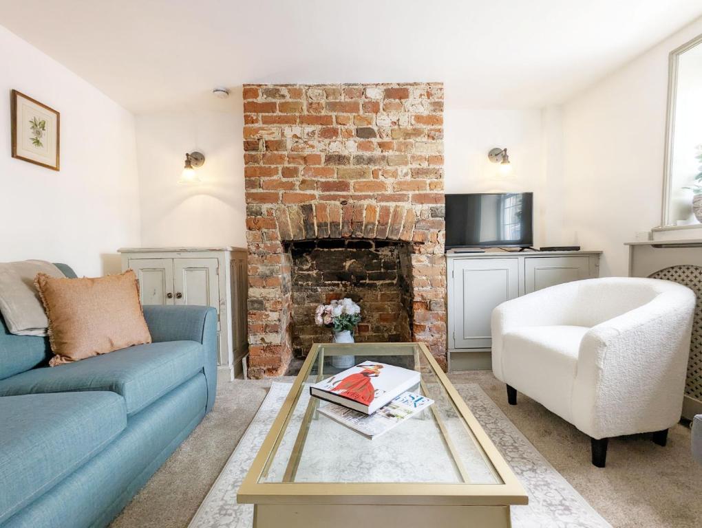 博格诺里吉斯June Cottage的客厅设有蓝色的沙发和砖砌壁炉