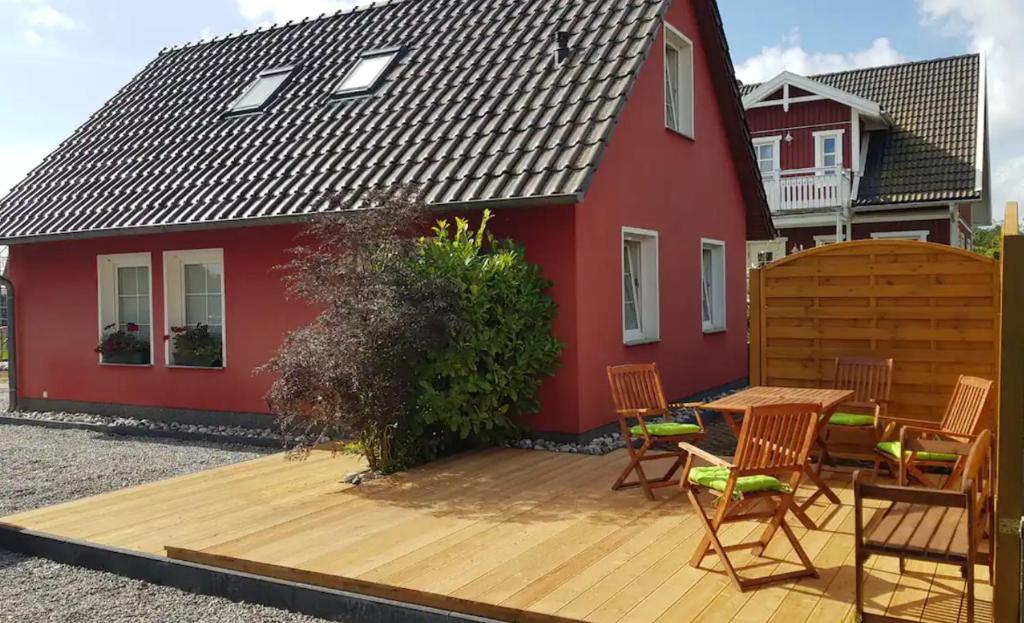 奥特里德维茨Ferienunterkunft Rügen 3, Alt Reddevitz 108, Insel Rügen, Sauna Nutzung möglich的红色房子前的木甲板上配有桌椅