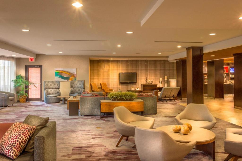 格林斯伯勒格林斯博罗机场万怡酒店的大堂配有沙发、椅子和电视。